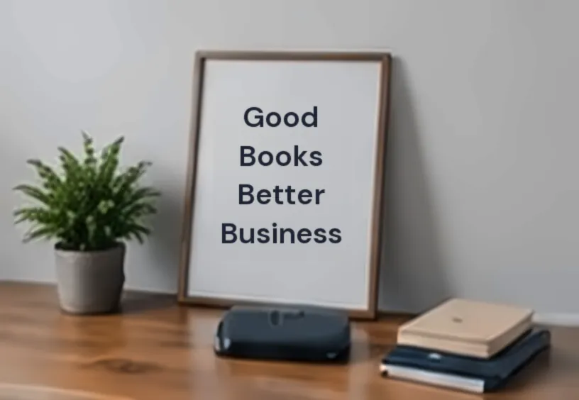 Framed sign reading Good Books Better Business on a wooden desk